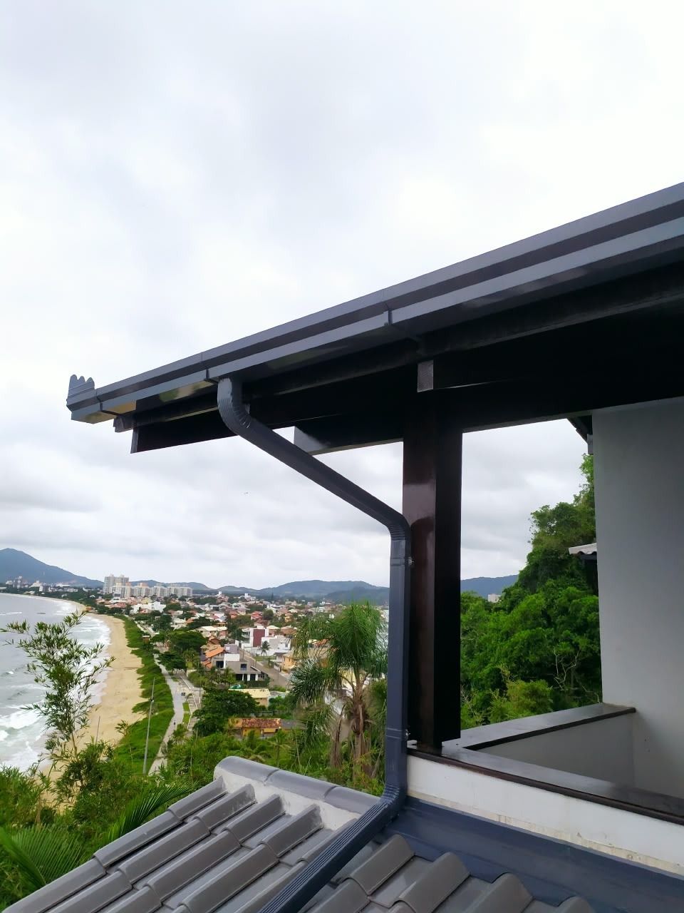 Calha e condutor de alumínio na cor preta instalados em residência com vista para o mar em Penha, SC