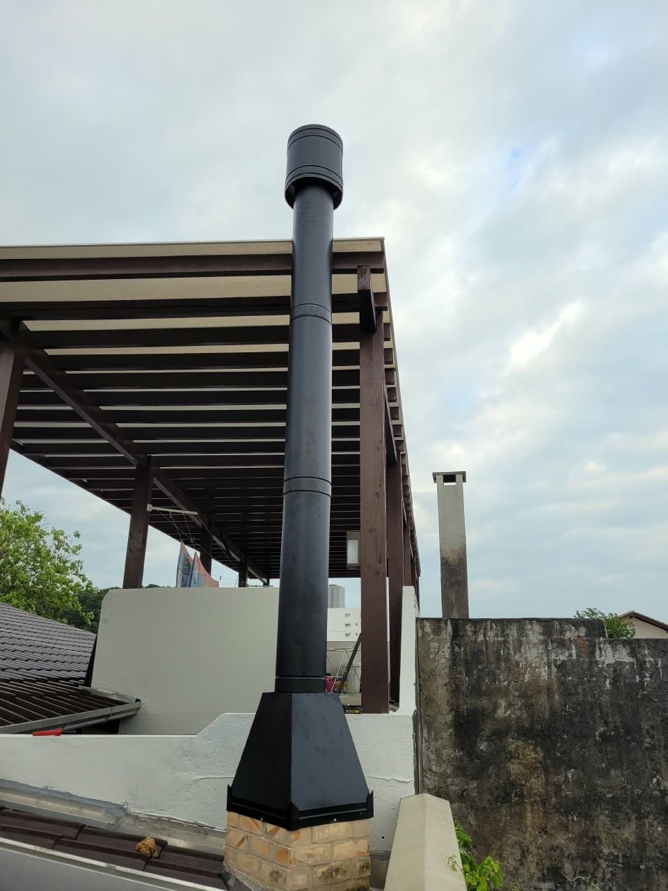 Chaminé preta alta instalada em área gourmet com pergolado em Penha, SC
