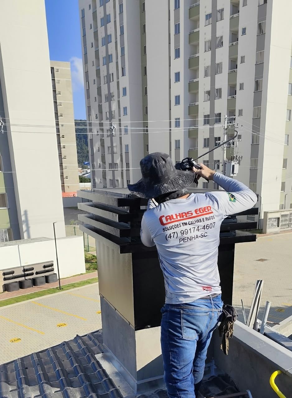 Equipe da Calhas Eger instalando coifa e chaminé em condomínio em Penha, SC